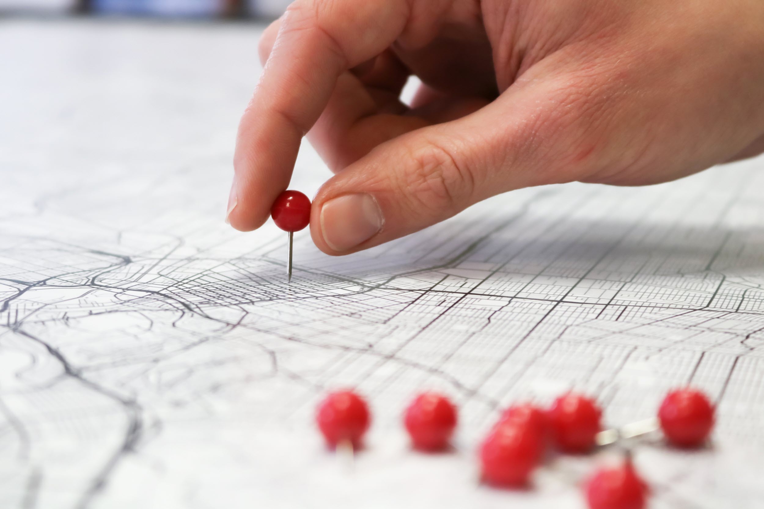 Hand placing a pin on a map