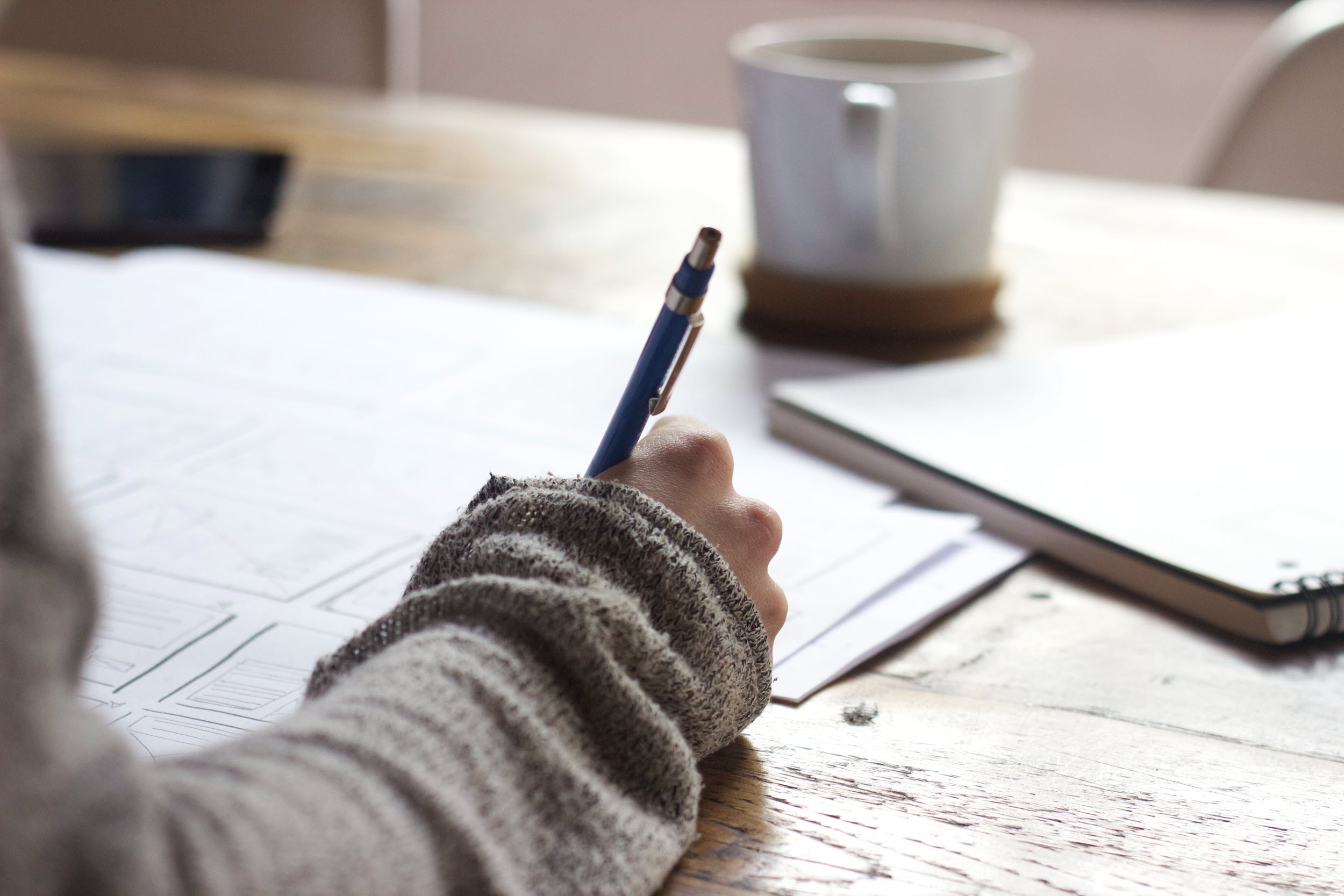 Hand taking notes at a desk